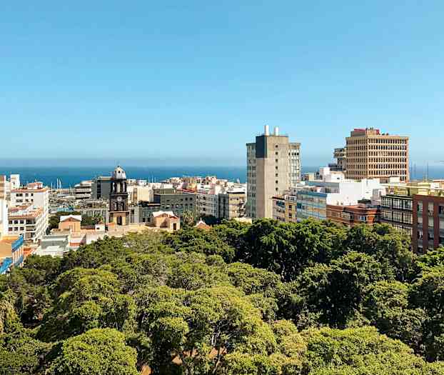 Kaupunki näkymä rakennuksineen ja viheralueineen, taustalla näkyy meri. (Tekoälyn luoma teksti)
