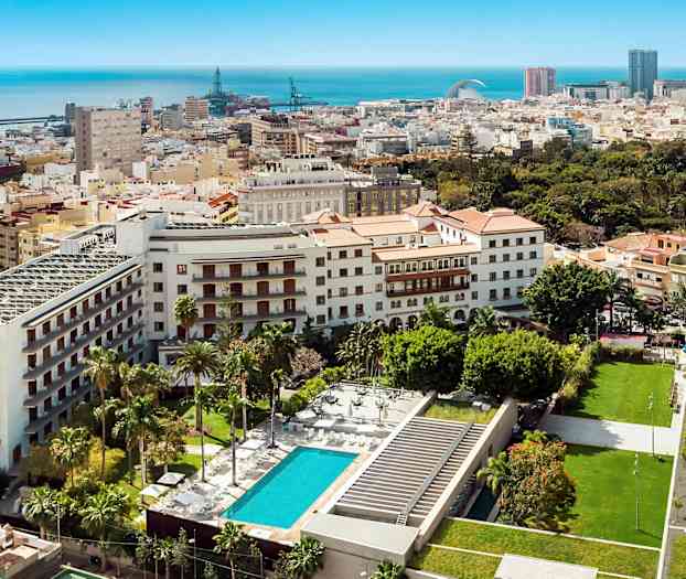 Näkymä kaupunkiympäristöstä, jossa rakennuksia, viheralueita ja uima-allas. (Tekoälyn luoma teksti)