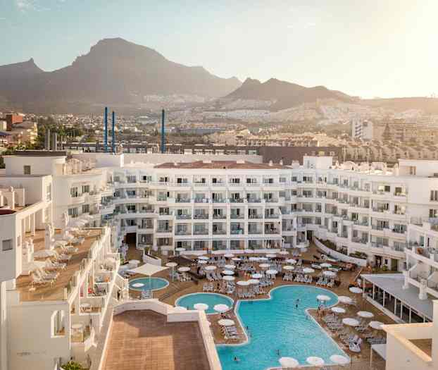 Näkymä hotellialueelle, jossa uima-altaita ja ympäröiviä vuoria. (Tekoälyn luoma teksti)