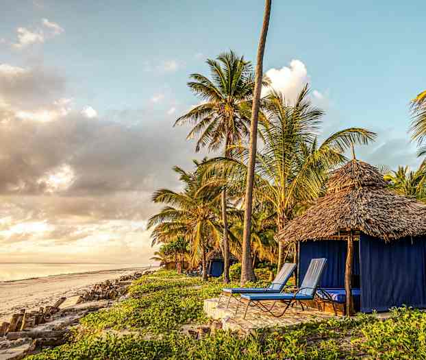 Ranta, jossa maja lähellä palmuja ja aurinkotuoleja. (Tekoälyn luoma teksti)