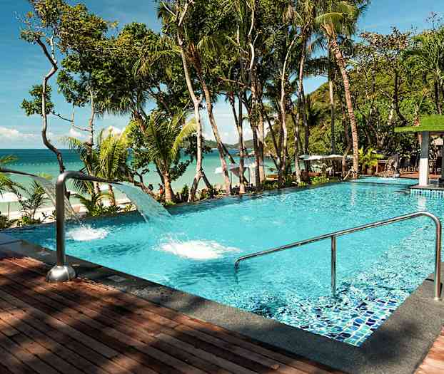 Uima-allas, jossa kirkasta sinistä vettä, trooppisten puiden ympäröimänä ja merinäköalalla. (Tekoälyn luoma teksti)