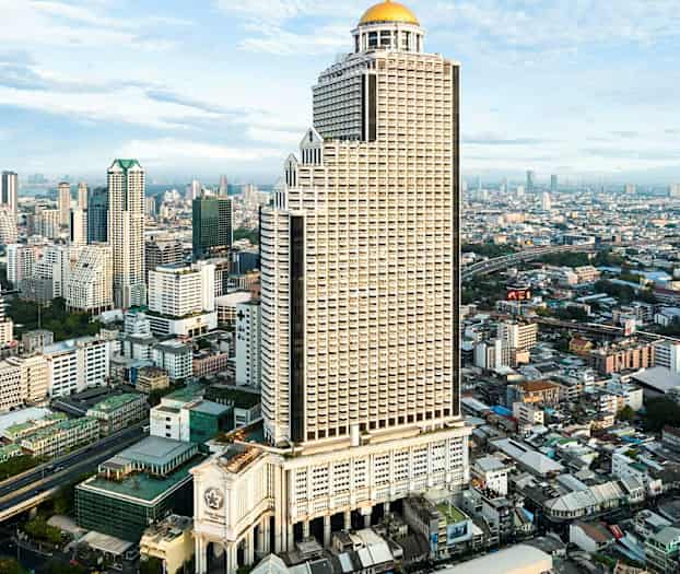 Korkea rakennus, jonka huipulla on kupoli, kaupunkinäkymässä, jossa on muita korkeita rakennuksia ja infrastruktuuria. (Tekoälyn luoma teksti)