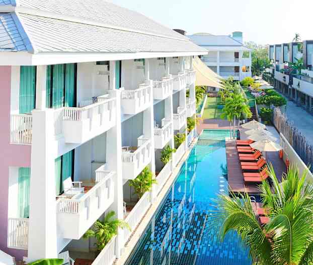 Hotelli, jossa on parvekkeita ja pitkä uima-allas aurinkotuolien ja päivänvarjojen vieressä. (Tekoälyn luoma teksti)