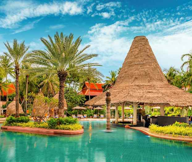 Allas, jossa on turkoosia vettä, ympäröitynä vehreillä palmuilla ja olkikattoisella rakennuksella. (Tekoälyn luoma teksti)