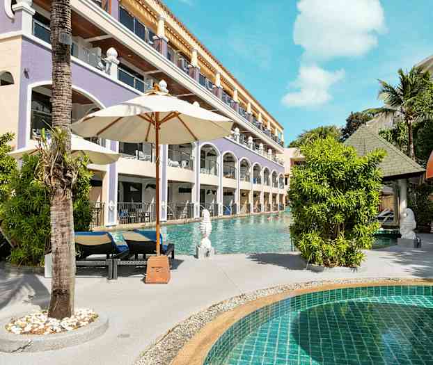 Uima-allas, jossa on aurinkotuoleja ja varjoja, lähellä hotellirakennusta. (Tekoälyn luoma teksti)