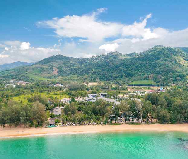 Maisema rannalla, vehreitä kukkuloita ja rakennuksia veden äärellä. (Tekoälyn luoma teksti)