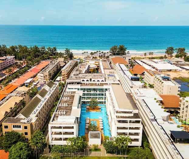 Hotellirakennus, jonka keskellä on uima-allas ja ympärillä useita rakennuksia lähellä merta. (Tekoälyn luoma teksti)