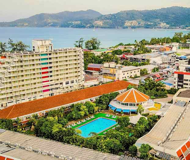 Näköala hotellikohteesta, jossa valkoinen monikerroksinen rakennus, uima-allas ja merinäköala. (Tekoälyn luoma teksti)