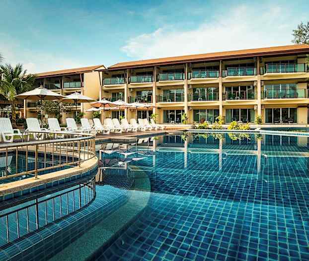 Kolmikerroksinen hotelli uima-altaan äärellä, jossa on aurinkotuoleja ja varjoja. (Tekoälyn luoma teksti)