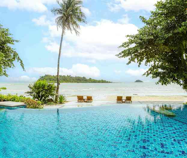 Näkymä ulkouima-altaalle etualalla, jossa on ranta ja meri taustalla, rehevien kasvien ja palmujen ympäröimänä. (Tekoälyn luoma teksti)