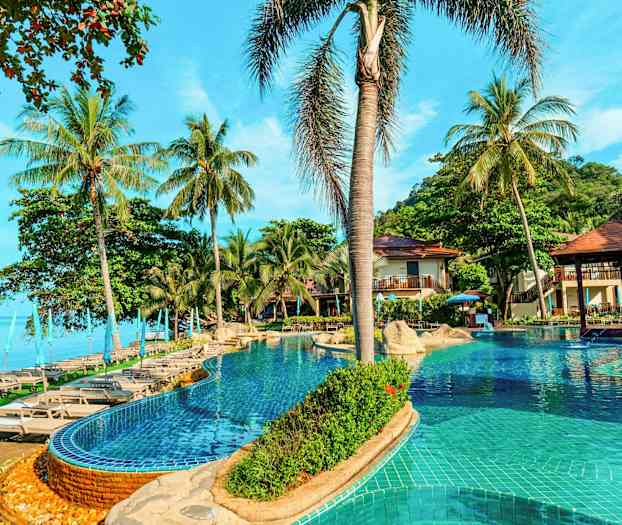 Uima-allas, jossa on aurinkotuoleja ja varjoja palmujen ympäröimänä meren vieressä. (Tekoälyn luoma teksti)