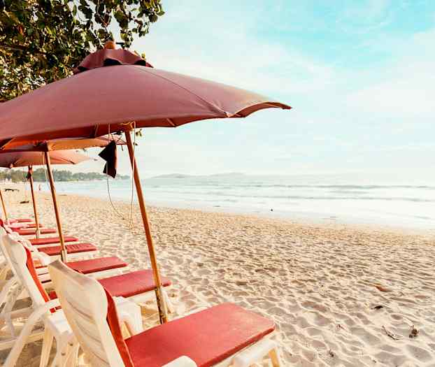 Ranta, jossa aurinkotuoleja ja aurinkovarjoja rivissä meren rannalla. (Tekoälyn luoma teksti)