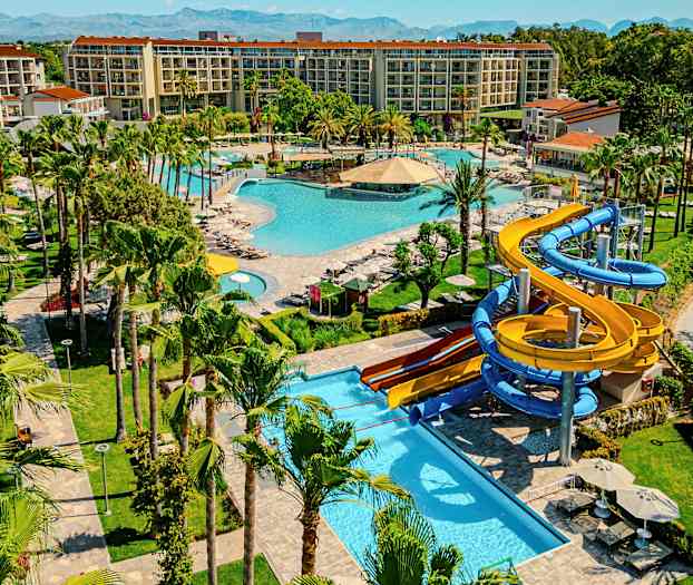 Lomakohde, jossa on useita uima-altaita, viheralueita ja vesiliukumäkiä. (Tekoälyn luoma teksti)