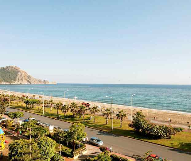 Rannikkoalue, jossa on ranta, meri ja tie vihreällä ympäristöllä. (Tekoälyn luoma teksti)