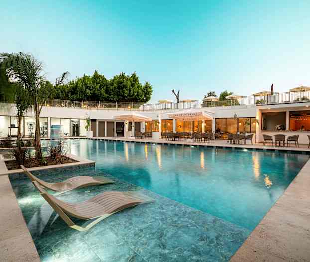 Ulkouima-allas aurinkotuoleilla ja ravintola taustalla. (Tekoälyn luoma teksti)