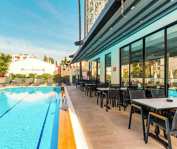 Hotellin uima-allas aurinkotuoleilla ja viereinen ruokailualue. (Tekoälyn luoma teksti)