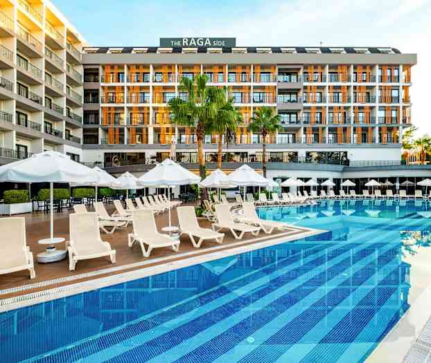 Hotelli uima-altaan äärellä, jossa on aurinkotuoleja ja aurinkovarjoja. (Tekoälyn luoma teksti)