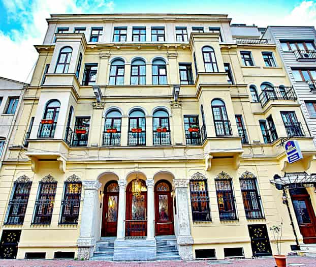 Vanhemman rakennuksen julkisivu parvekkeineen ja koristeltuine ikkunoineen. (Tekoälyn luoma teksti)