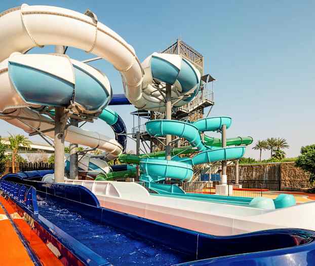 Kuva ulkoilmassa olevista vesiliukumäistä, jotka ovat eri värejä. (Tekoälyn luoma teksti)