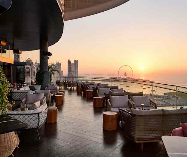 Terassi, jolla istumapaikkoja ja merinäkymä auringonlaskun aikaan. (Tekoälyn luoma teksti)