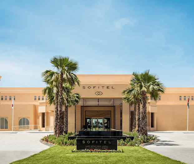 Sofitel-hotellin etupuoli, jossa palmuja ja lippuja. (Tekoälyn luoma teksti)