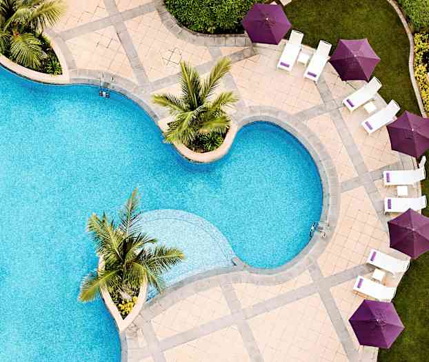 Ulkouima-allas, jonka ympärillä on tuoleja ja violetteja aurinkovarjoja. (Tekoälyn luoma teksti)