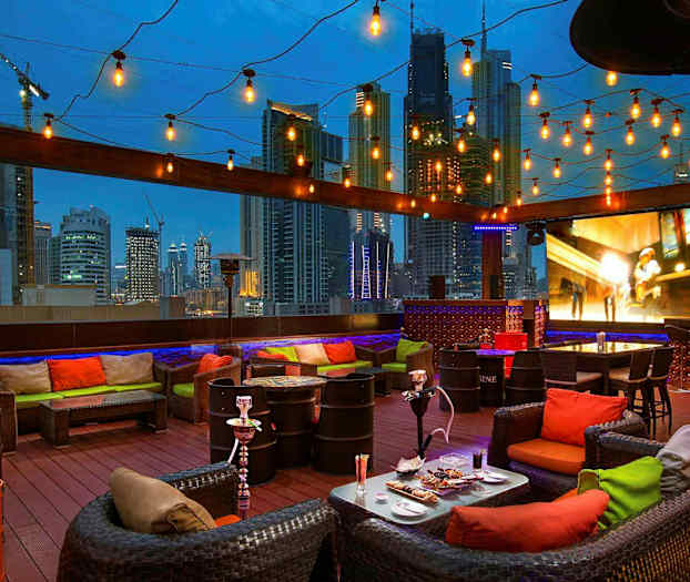 Katuterassi, jossa on istuinryhmiä, koristevaloja ja näkymä kaupunkisiluettiin illalla. (Tekoälyn luoma teksti)