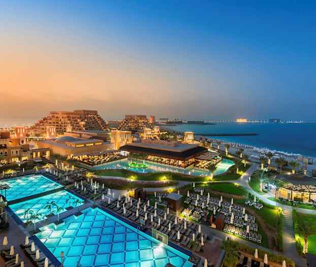 Näkymä hotellialueesta rakennuksineen, uima-altaineen ja rannalla meren äärellä. (Tekoälyn luoma teksti)