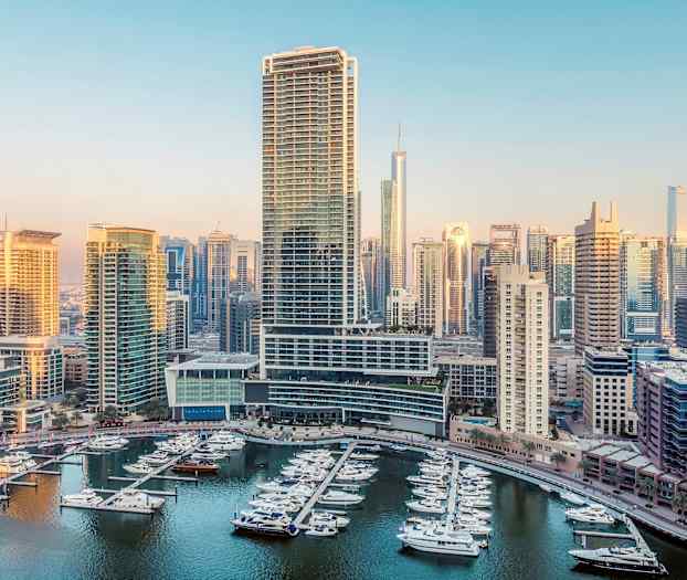 Näköala satamaan, jossa on veneitä ja korkeat rakennukset taustalla. (Tekoälyn luoma teksti)