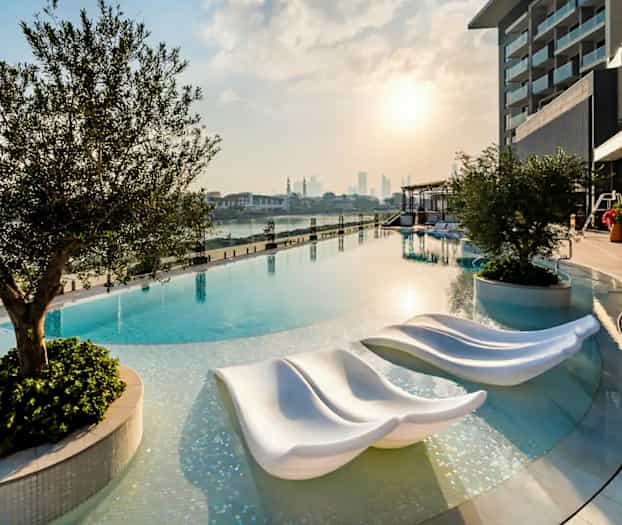 Kuva infinity-altaasta auringonlaskun aikaan, nykyaikaiset aurinkotuolit ja ympäröivää vehreyttä. (Tekoälyn luoma teksti)