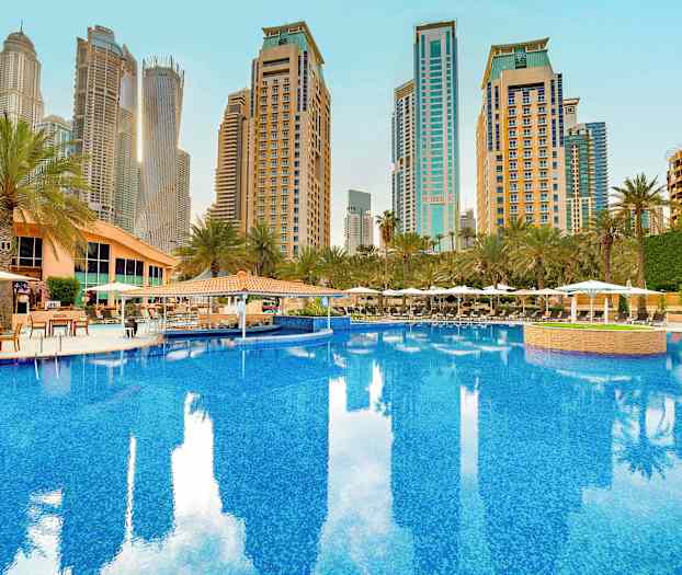 Suuri uima-allas, jota ympäröivät palmut ja rakennukset. (Tekoälyn luoma teksti)