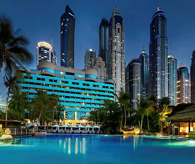 Hotelli, jossa on sininen julkisivu, uima-altaan äärellä ja taustalla korkeita rakennuksia. (Tekoälyn luoma teksti)