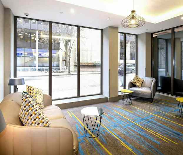 Huone, jossa suuret ikkunat, nojatuolit ja pienet pöydät. (Tekoälyn luoma teksti)