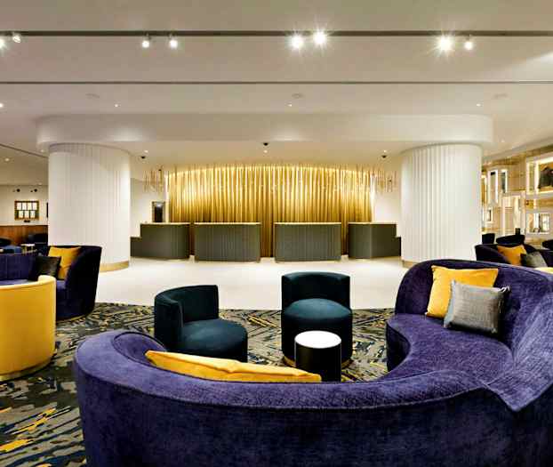 Hotellin vastaanotto, nykyaikaiset kalusteet ja lämmin valaistus. (Tekoälyn luoma teksti)