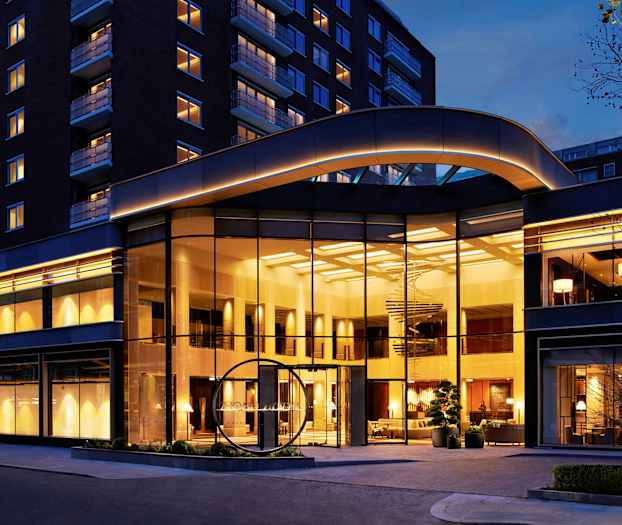 Hotellirakennus, jossa suuri lasijulkisivu ja iltavalaistus. (Tekoälyn luoma teksti)