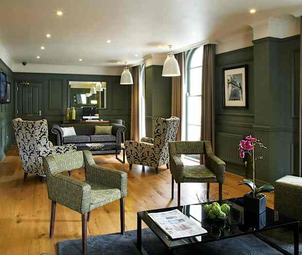 Tyylikäs hotellin oleskelutila, jossa nojatuoleja ja sohvia, koristekasveja ja moderni sisustus. (Tekoälyn luoma teksti)