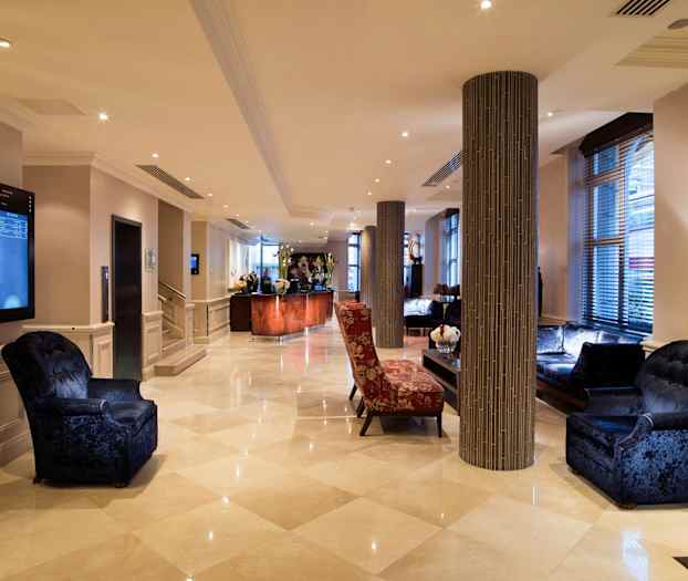 Hotellin aula, jossa istuimia ja vastaanottotiski. (Tekoälyn luoma teksti)