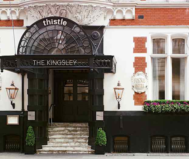 Hotellin sisäänkäynti portailla, kyltti ja kukkia. (Tekoälyn luoma teksti)