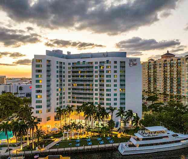 Rakennus, jossa on parvekkeita, uima-allas ja vene. Taustalla näkyy lämmin auringonlasku. (Tekoälyn luoma teksti)