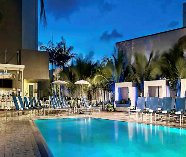 Ulkouima-allas, jonka ympärillä on aurinkotuoleja ja cabanoita, sekä baari taustalla palmujen ympäröimänä. (Tekoälyn luoma teksti)