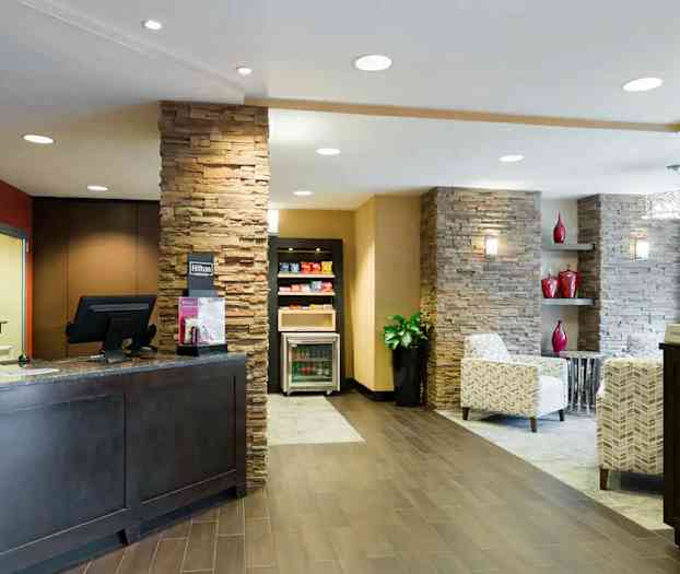 Hotellin vastaanottotila tyylikkäällä sisustuksella, mukaan lukien kiviseinät ja mukavat istuimet. (Tekoälyn luoma teksti)