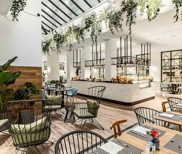 Moderni ravintola, jossa tyylikkäät kalusteet ja vihreitä kasveja. (Tekoälyn luoma teksti)