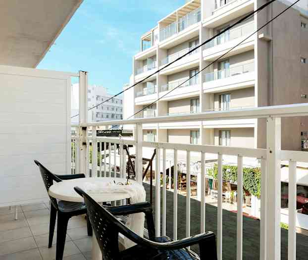 Parveke, jossa on kaksi tuolia ja pöytä, näkymä rakennuksiin. (Tekoälyn luoma teksti)