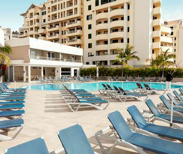 Ulkouima-allas aurinkotuoleineen ja ympäröivät rakennukset. (Tekoälyn luoma teksti)