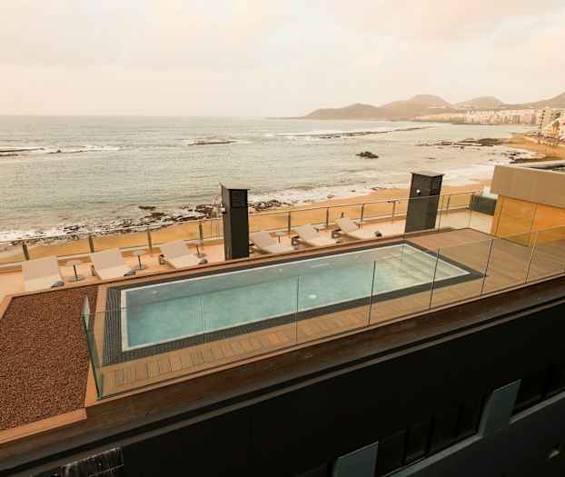 Kattouima-allas aurinkotuoleilla ja näkymä merelle ja rannalle. (Tekoälyn luoma teksti)