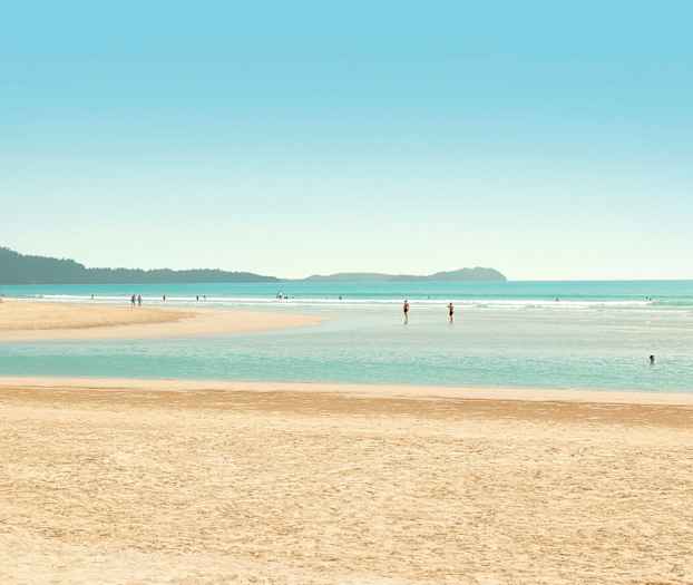 Ranta, jossa ihmisiä uimassa ja kävelemässä vedessä. (Tekoälyn luoma teksti)