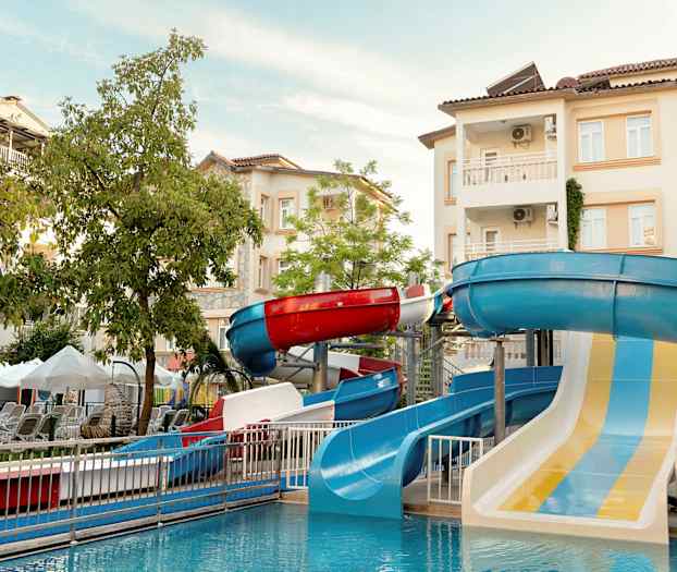 Kuva vesipuistosta, jossa on vesiliukumäkiä ja taustalla rakennuksia. (Tekoälyn luoma teksti)