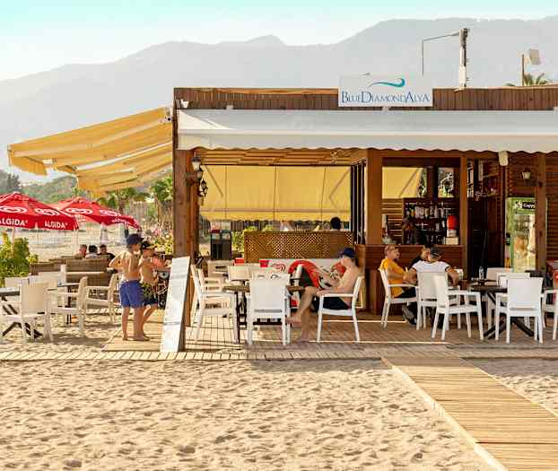 Rantala-ravintola ulkoterassilla ja aurinkotuoleilla, vuoria taustalla. (Tekoälyn luoma teksti)