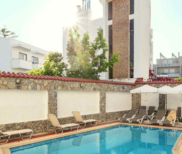 Pieni ulkouima-allas, jota ympäröivät aurinkotuolit ja rakennukset. (Tekoälyn luoma teksti)