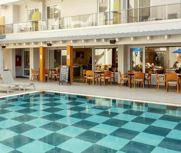 Ulkouima-allas, jonka pohjassa ruutukuvio, hotellirakennuksen parvekkeiden ja ravintolan edessä. (Tekoälyn luoma teksti)